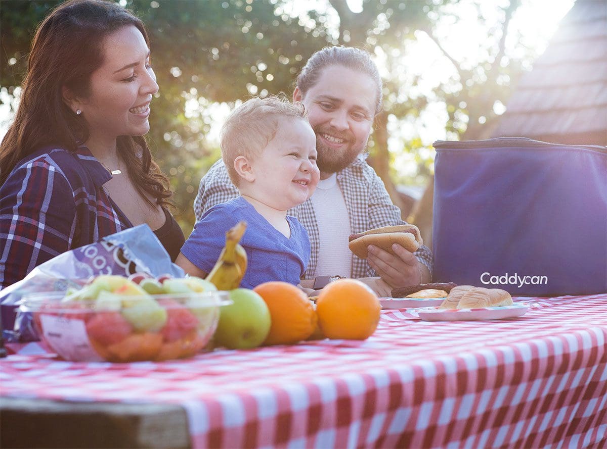 A family sitting at the table with fruit and a laptop.