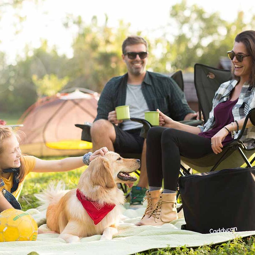 A family sitting on the grass with their dog.
